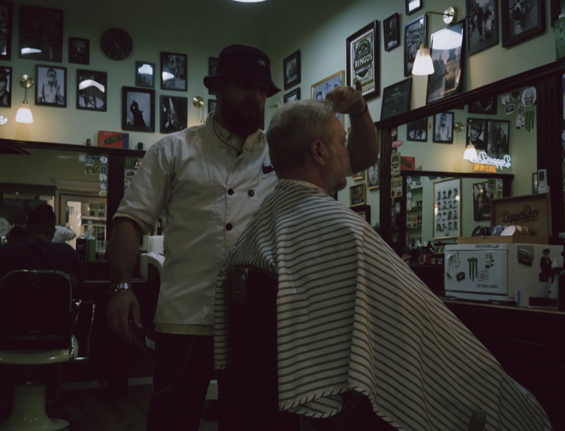 A barber at Ringo's barbershop styling a client's haircut in a classic barber chair